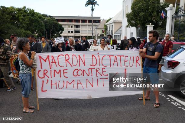 Protesters hold a banner reading 'Dictator Macron - Crimes against humanity' in front of the prefecture in Saint-Denis on the French Indian Ocean...