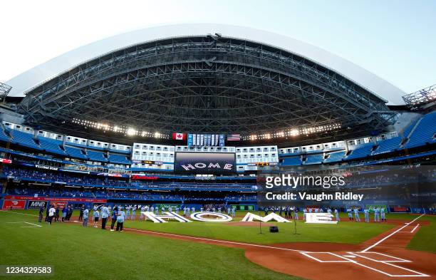 The Toronto Blue Jays line up behind a 'Home' sign to commemorate their first home game in Toronto this season prior to a MLB game against the Kansas...