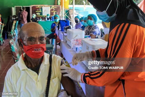 An elderly Papuan man receives the Sinovac vaccine for Covid-19 from a health official during a mass vaccination programme at a military district...