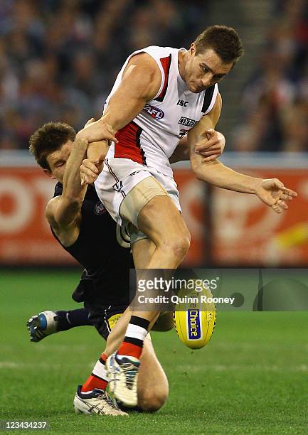 Sam Fisher of the Saints kicks whilst being tackled by Bryce Gibbs of the Blues during the round 24 AFL match between the Carlton Blues and the St...