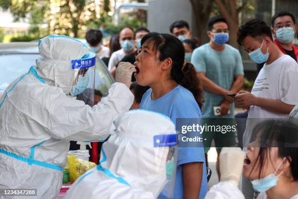 Woman receives a nucleic acid test for the Covid-19 coronavirus in Zhengzhou, in China's central Henan province on July 31, 2021. - China OUT / China...