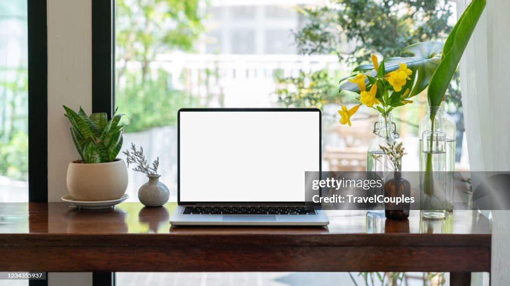 Laptop computer blank white screen on table in cafe background. Laptop with blank screen on table of coffee shop blur background.