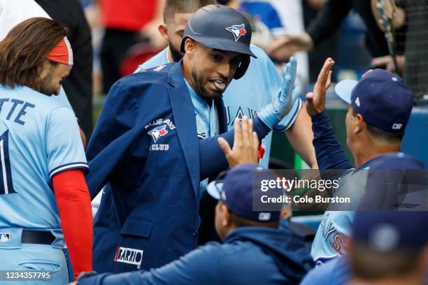 George Springer of the Toronto Blue Jays celebrates in the dugout with teammates after hitting a home run in the first inning during their MLB game...