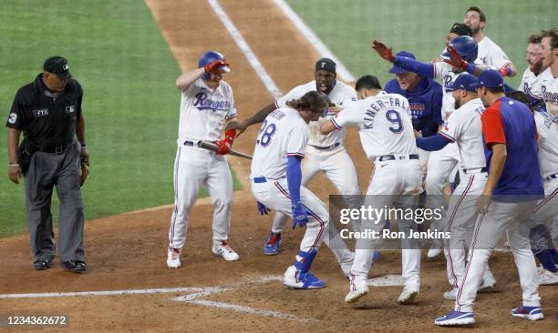 Jonah Heim of the Texas Rangers celebrates with teammates after hitting a two -run walk-off home run to defeat Seattle Mariners 5-4 in ten innings at...