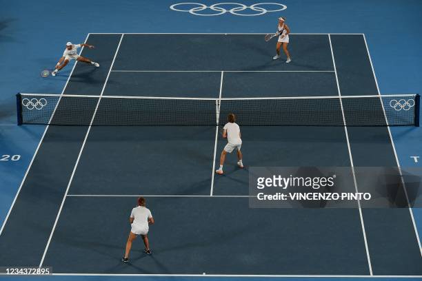 Russia's Aslan Karatsev returns a shot to Russia's Anastasia Pavlyuchenkova and Russia's Andrey Rublev as Russia's Elena Vesnina looks on during the...