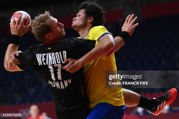 Germany's right back Steffen Weinhold is challenged by Brazil's left back Thiagus Petrus during the men's preliminary round group A handball match...