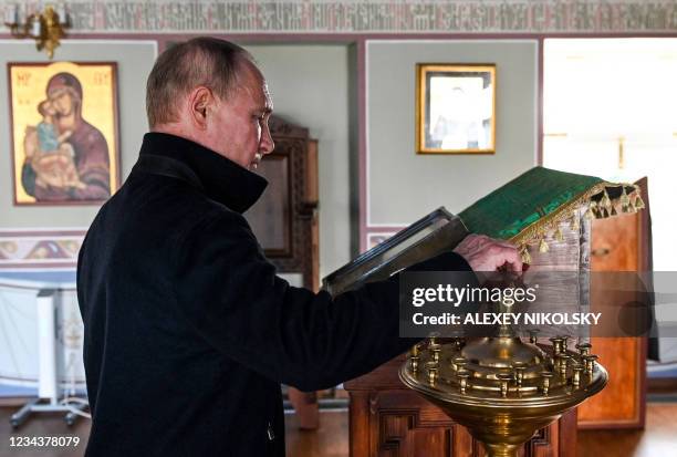 Russian President Vladimir Putin lights a candle during his visit to the Konevsky Monastery on the Konevets Island in the Ladoga lake, Leningrad...