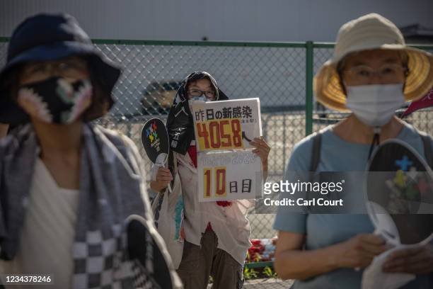 Demonstrator hold a placard showing the number of coronavirus cases from the previous day during an anti-Olympics protest outside Ariake Gymnastics...