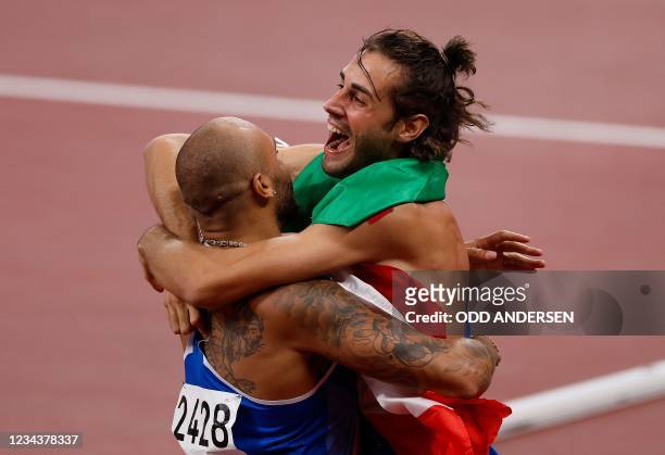 Italy's Lamont Marcell Jacobs celebrates with Italian high jumper Gianmarco Tamberi after winning the men's 100m final during the Tokyo 2020 Olympic...