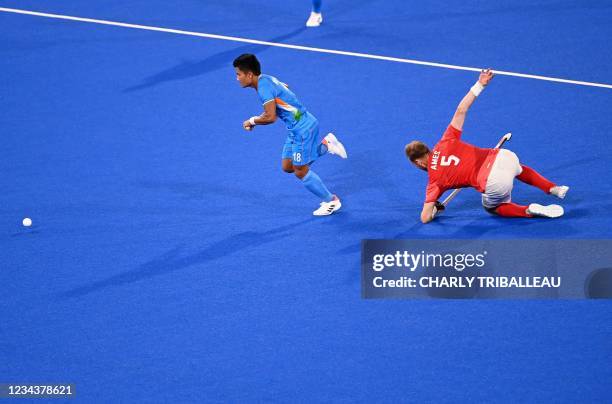 India's Nilakanta Sharma carries the ball past Britain's David Ames during their men's quarter-final match of the Tokyo 2020 Olympic Games field...