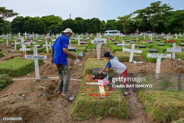 Relatives visit the grave of a loved one at a cemetery, which no longer accepts burials after its plots were filled amid the Covid-19 coronavirus...