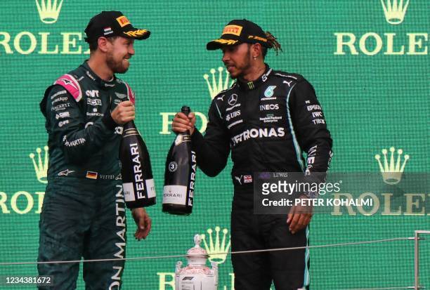 Aston Martin's German driver Sebastian Vettel and British driver Lewis Hamilton celebrate with champagne on the podium after the Formula One...