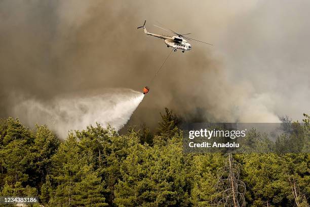 Smoke rises as a helicopter responds to the forest fire that broke out in Manavgat district in Antalya, Turkey on August 01, 2021. Ground and air...