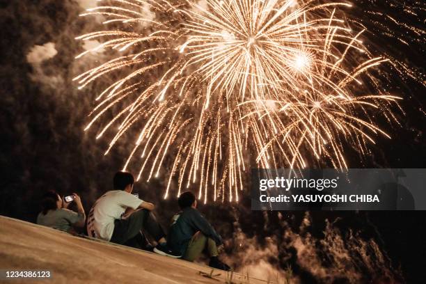 People watch the fireworks on a seawall reconstructed after the tsunami hit in 2011, in Minamisoma, Fukushima prefecture on August 1, 2021. - The...