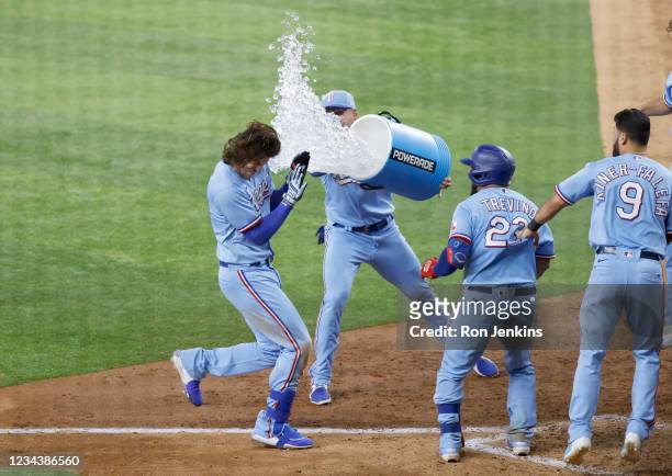 Jonah Heim of the Texas Rangers is hit with a bucket of water after by teammate Brock Holt after hitting a walk off solo home run to defeat the...