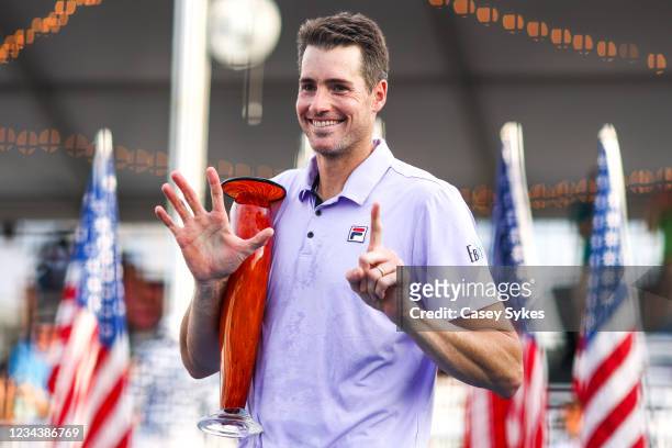 John Isner of the United States holds up six fingers, signifiying his six Atlanta Open victories, while holding the winners trophy after winning the...