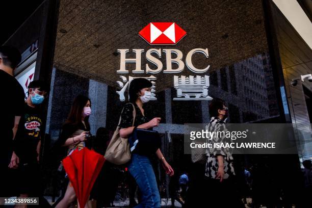 Pedestrians walk past the logo for HSBC outside a local branch bank in Hong Kong on August 2, 2021.