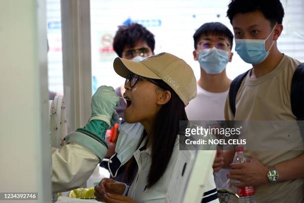 Swab sample is taken from a woman to be tested for the Covid-19 coronavirus at a hospital in Beijing on August 2 amid the country's most widespread...