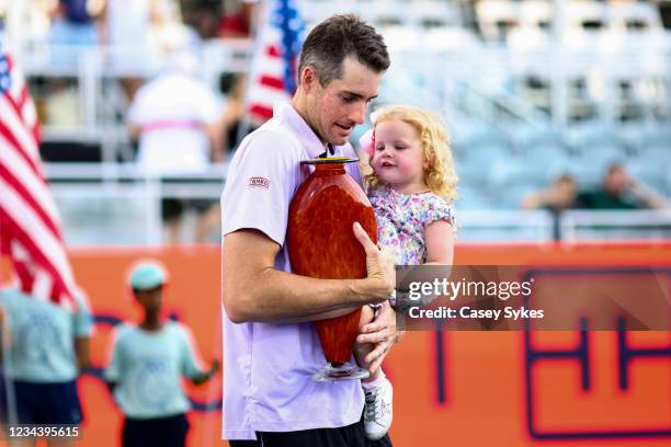 John Isner of the United States holds his daughter, Hunter Grace, in one arm and the winners trophy in the other at the Truist Atlanta Open at...