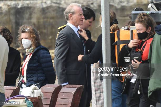 The tie of Andrew Havill is adjusted by a crew member as he stands in the harbour during filming for the Netflix series "The Crown" on August 2, 2021...