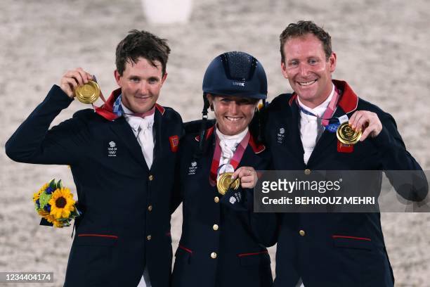 Gold medallists Britain's Oliver Townend, Laura Collett and Tom McEwen celebrate on the podium of the equestrian's eventing jumping team final during...