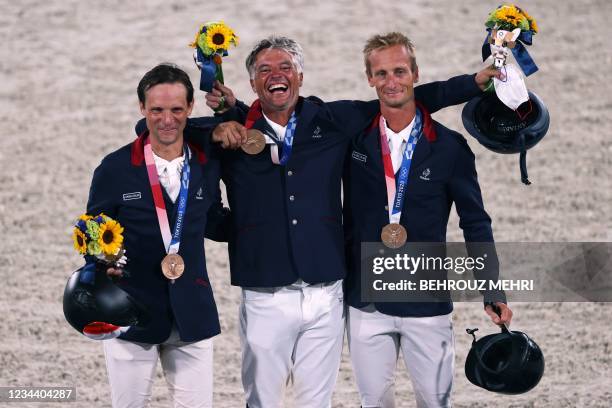 Bronze medallists France's Karim Florent Laghouag, Nicolas Touzaint and Christopher Six celebrate on the podium of the equestrian's eventing jumping...