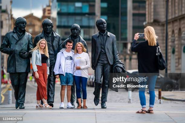 People pose for photographs beside statues of The Beatles in Liverpool, U.K., on Monday, Aug. 2, 2021. Just 17 years after Liverpool was listed as a...