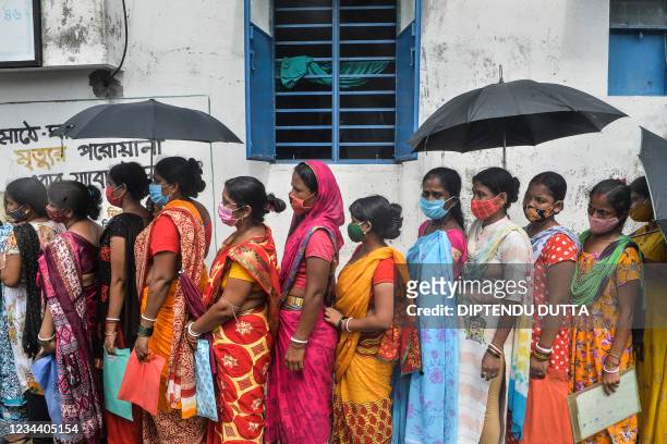 Women stand in a queue as they wait to receive a dose of the Covishield vaccine against the Covid-19 coronavirus at a primary health centre in...