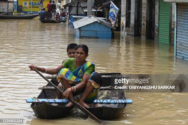 Residents ride a boat over a road submerged by floodwaters following heavy monsoon rains in Ghatal, Paschim Medinipur district, about 100 km from...