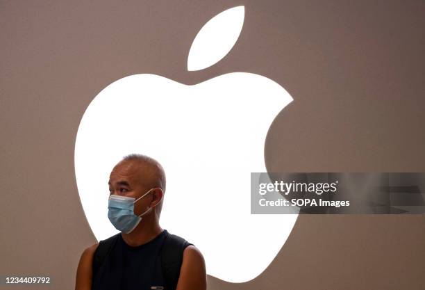 Man wearing a face mask is seen standing in front of the American multinational technology company Apple logo and store in Hong Kong.