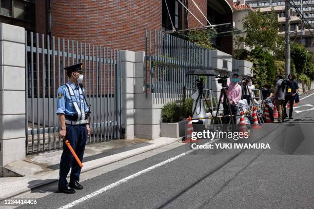 Police officer and members of the press stand outside the Polish embassy in Tokyo on August 3 where Belarus athlete Krystsina Tsimanouskaya is...