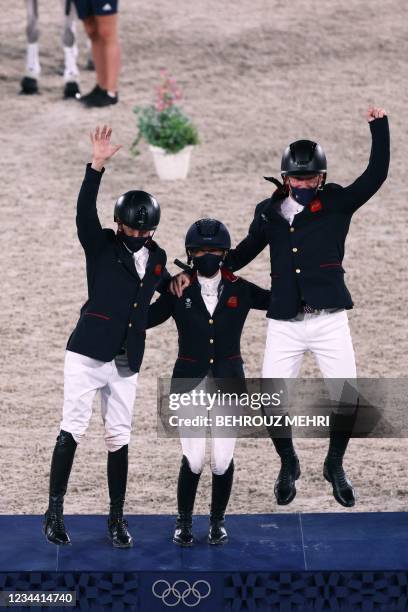 Gold medalists Britain's Tom McEwen, Laura Collett and Oliver Townend celebrate on the podium of the equestrian's eventing jumping team final during...