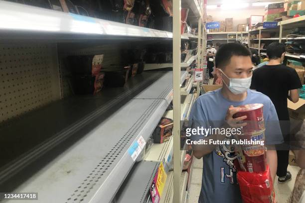 People buy the necessities in a panic shopping in a supermarket after several nearby residential blocks went into lockdown in the COVID-19 prevention...