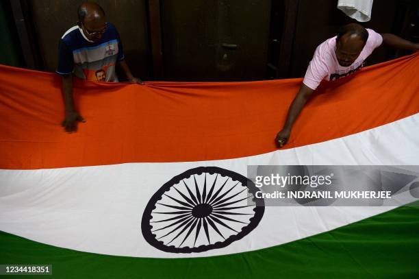 Workers inspect an Indian national flag ahead of the country's 75th Independence Day celebrations at a workshop in Mumbai on August 3, 2021.