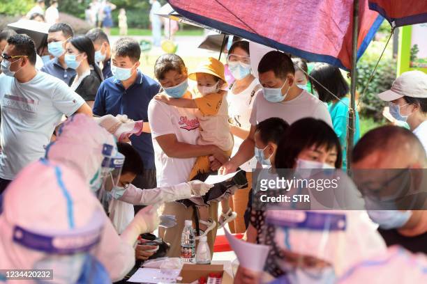 Residents queue to take nucleic acid tests for the coronavirus in Wuhan in China's central Hubei province on August 3 as the city tests its entire...