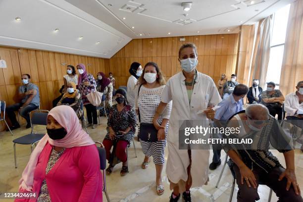 Tunisians wait for their turn to be vaccinated at El-Menzah Stadium which was turned into a vaccination centre in the capital Tunis on August 3,...