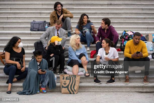 Rep. Alexandria Ocasio-Cortez talks with activists as they protest the expiration of the federal eviction moratorium on the House steps of the U.S....