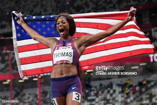 S Gabrielle Thomas celebrates with the flag of the USA after placing third of the women's 200m final during the Tokyo 2020 Olympic Games at the...