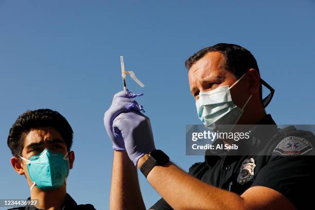 Kyle Carson, right, EMT with FirstMed Ambulance Services prepares the Pfizer Covid vaccine as the Fernandeno Tataviam Band of Mission Indians, in its...