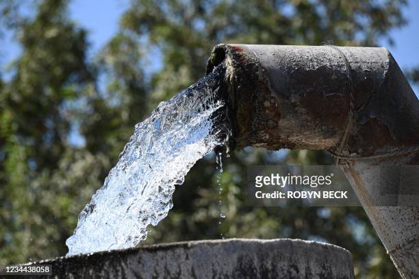 Water pumped up from an underground well flows into a cistern on a farm in Fresno, California, July 24, 2021. Central Valley farmers, desperate for...
