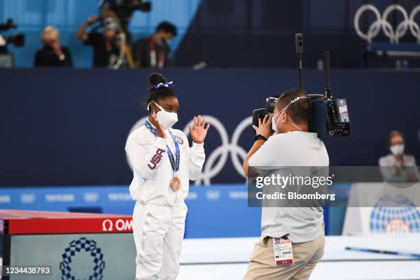 Simone Biles of Team United States poses for a television cameraman after she won the bronze medal on the balance beam at the Tokyo 2020 Olympic...