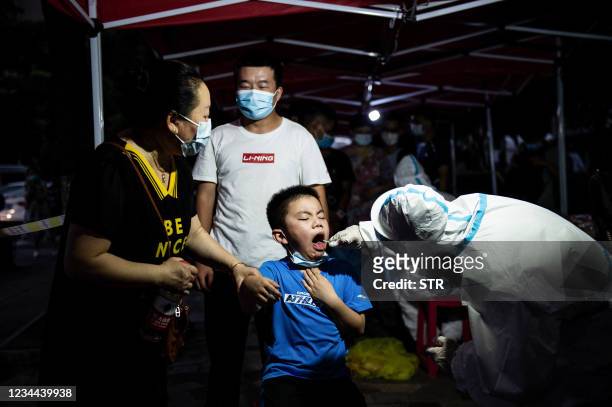 This photo taken on August 3, 2021 shows a child receiving a nucleic acid test for the coronavirus in Wuhan in China's central Hubei province. -...