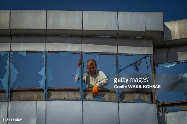 Graphic content / A man removes broken glass from the windows in the facade of a supermarket a day after a car bomb explosion in Kabul on August 4,...