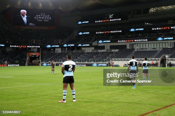 Sharks and Tigers players pay their respect during a minutes silence for the late Arthur Summons during the round three NRL match between the...