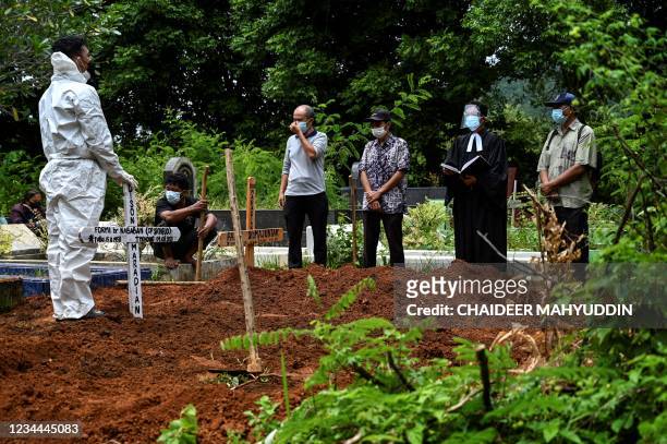 Relatives pray after lowering the coffin of a victim of the COVID-19 coronavirus at a cemetery at Darul Imarah the outskirt of Banda Aceh on August...