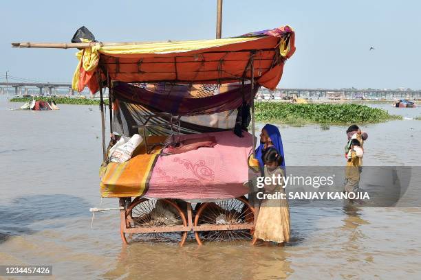 Vendors move their belongings in a flooded area on the banks of the River Ganges in Allahabad on August 4 as the water levels of the Ganges and...