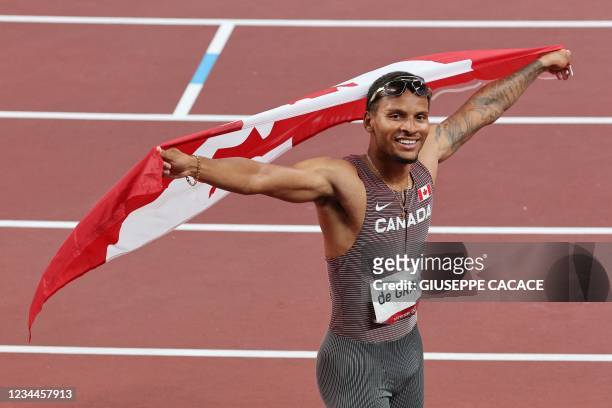 Canada's Andre De Grasse celebrates with the Canadian national flag after winning the men's 200m final during the Tokyo 2020 Olympic Games at the...