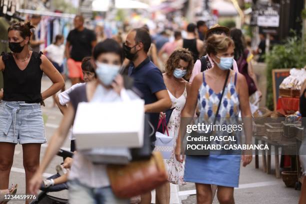 People wearing protective face masks shop along Fesch street in Ajaccio's touristic district on August 4 as health officials activated an emergency...