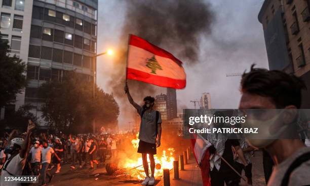 Protester stands with a Lebanese national flag during clashes with army and security forces near the Lebanese parliament headquarters in the centre...