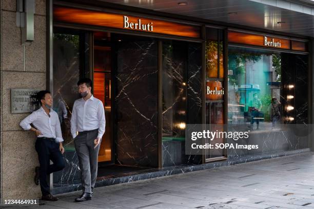 Men having a conversation next to the Italian fashion brand Berluti store in Hong Kong.